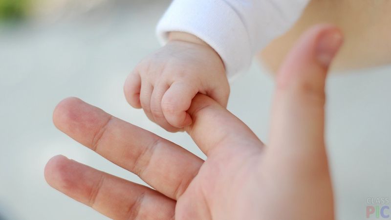 Младенец держит за палец